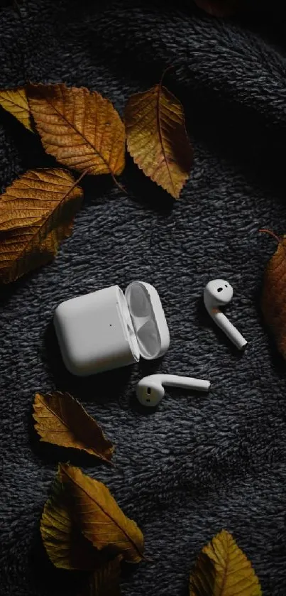 AirPods on textured blanket with autumn leaves, creating a cozy fall vibe.