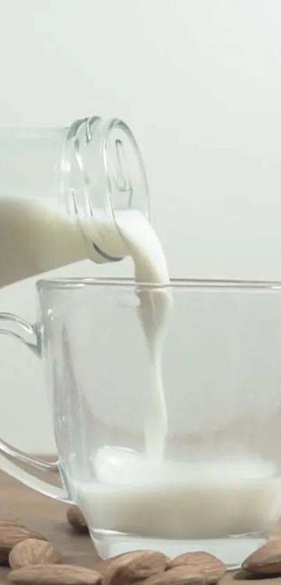 Almond milk being poured into a glass mug on a wooden table with almonds.