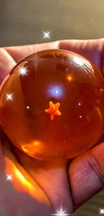 Hand holds an amber sphere glowing warmly, featuring a small star inside.