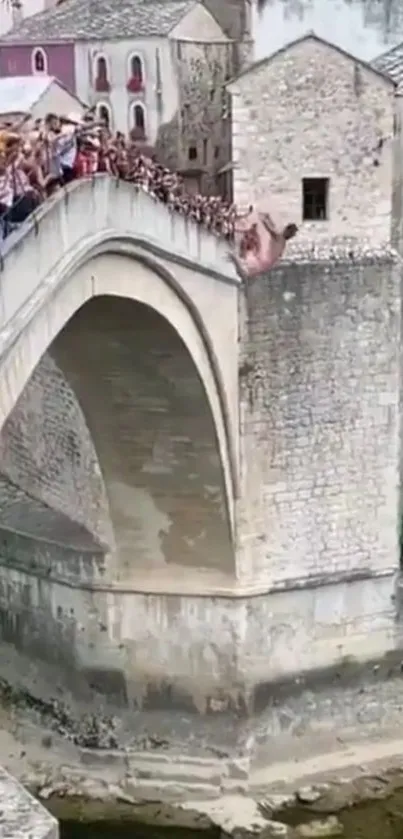 Tourists on ancient stone bridge over scenic river.