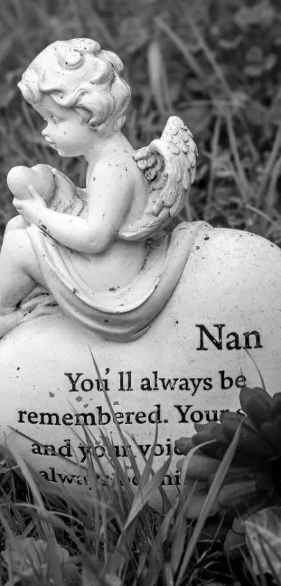 Black and white photo of an angel statue on a heart-shaped stone in the grass.