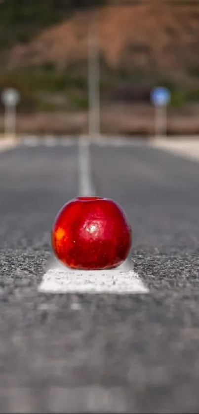 Red apple placed on a lonely road with a blurred background.