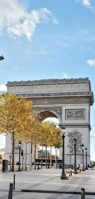 Arc de Triomphe with autumn trees under a bright blue sky.