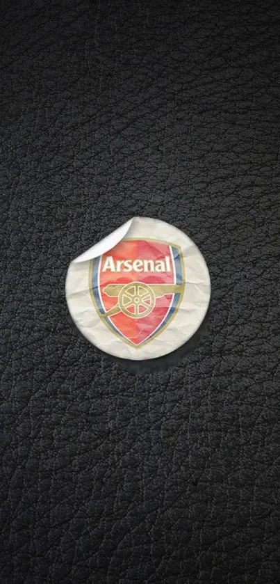 Arsenal emblem sticker on black leather texture background.