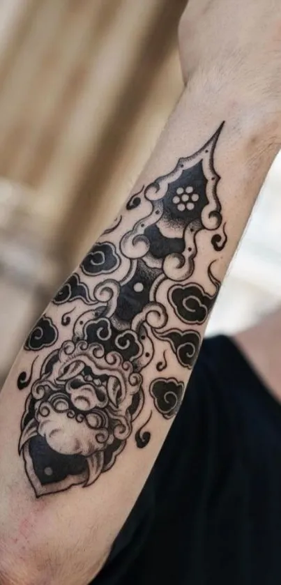 Intricate black ink arm tattoo design against a blurred background.