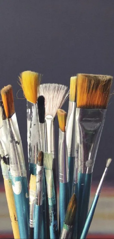 Collection of paintbrushes with abstract backdrop in dark purple tones.