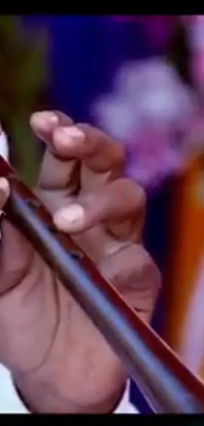 Close-up of hands playing a flute with a vibrant background.