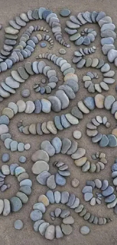 A circle of artfully arranged pebbles on a grey sandy surface, ideal for phone wallpaper.