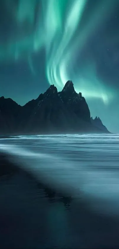 Aurora Borealis over mountains reflecting in calm water.