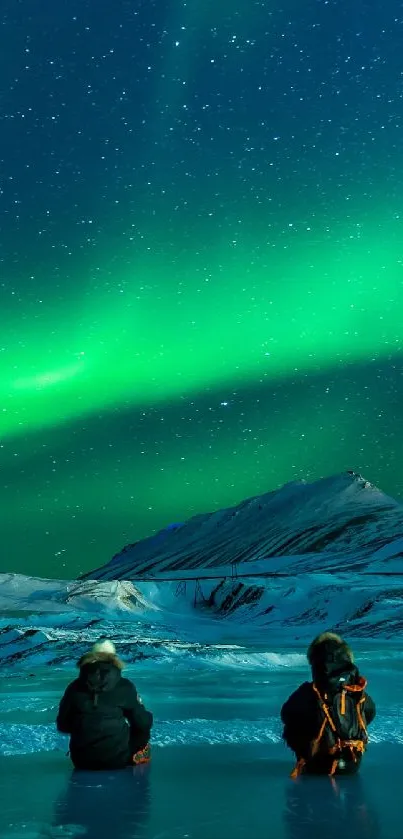 Aurora borealis lights up the night sky over a snowy landscape with two people.