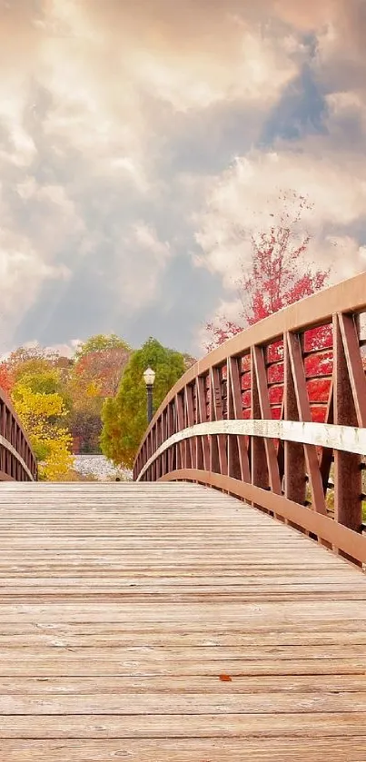 Wooden bridge surrounded by autumn foliage under a cloudy sky.