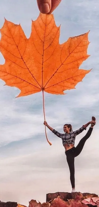 Person balancing with large autumn leaf against blue sky.