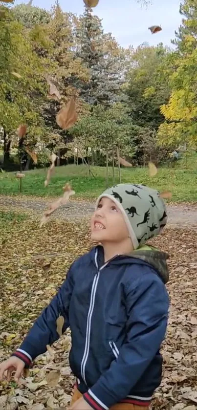 Child enjoys falling leaves in autumn park.