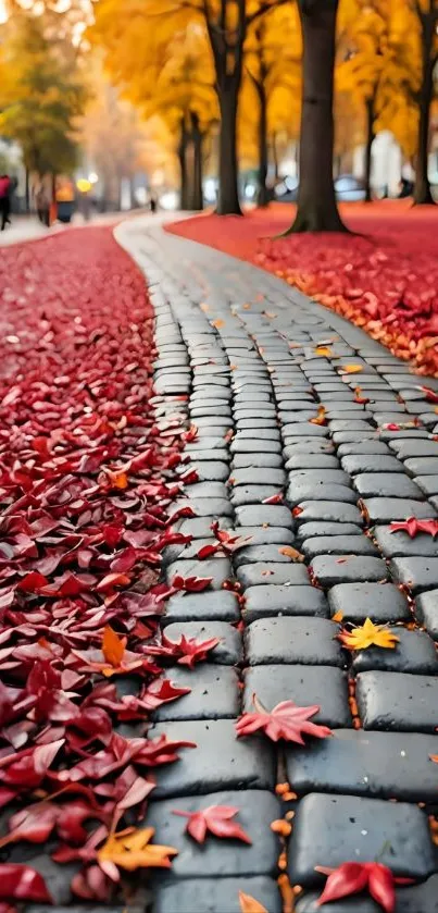 Vibrant autumn path lined with fallen red and yellow leaves on cobblestone.