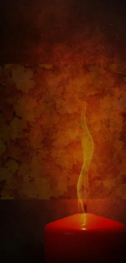 Glowing red candle with autumn leaves background.