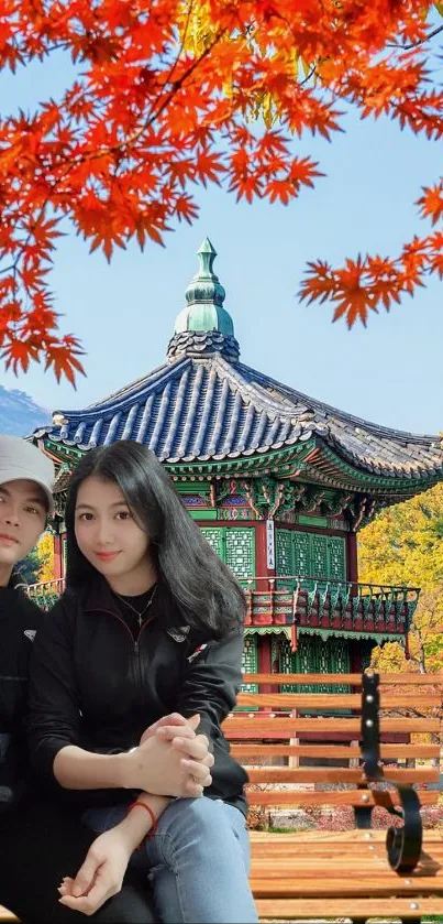 Couple in front of Asian pavilion with colorful autumn leaves.