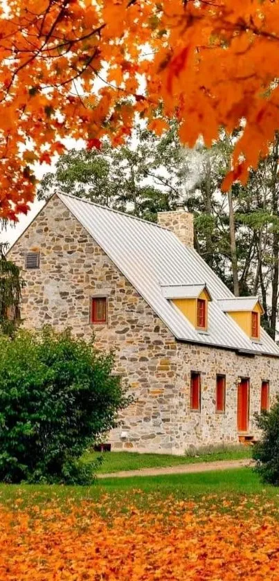 Stone cottage surrounded by orange autumn leaves.