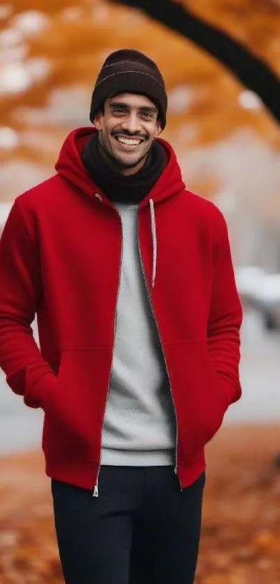 Man in red hoodie smiling in autumn park with orange leaves.