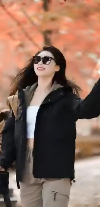 Woman walking in a park with autumn leaves and stylish outfit.