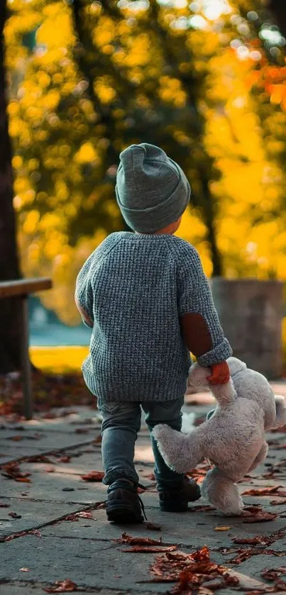 Child walking in autumn holding a teddy bear.