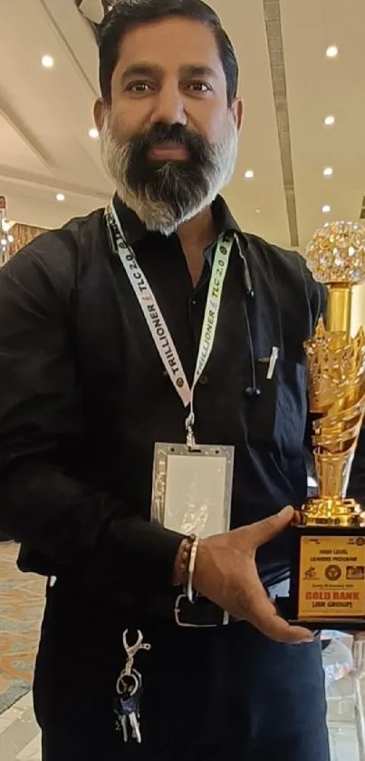 A person proudly holding a trophy at an award ceremony event.