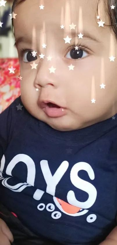 Cute baby in a dark blue shirt amid star effects in wallpaper.