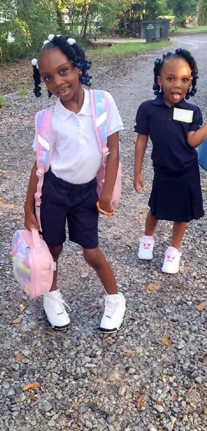 Two young girls in school uniforms, smiling outdoors.