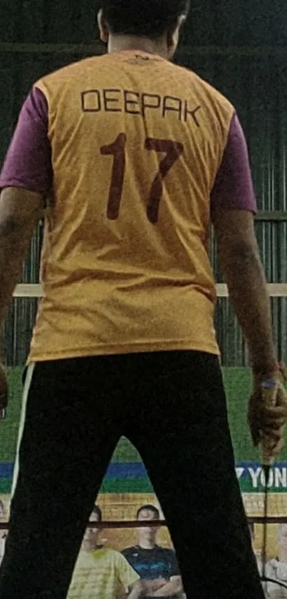 Badminton player in orange jersey on green court.