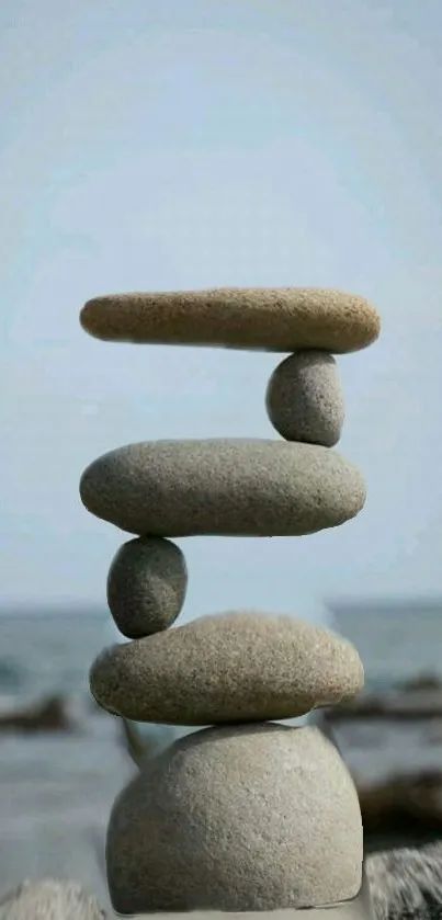 Stack of balanced stones against ocean backdrop, serene wallpaper.