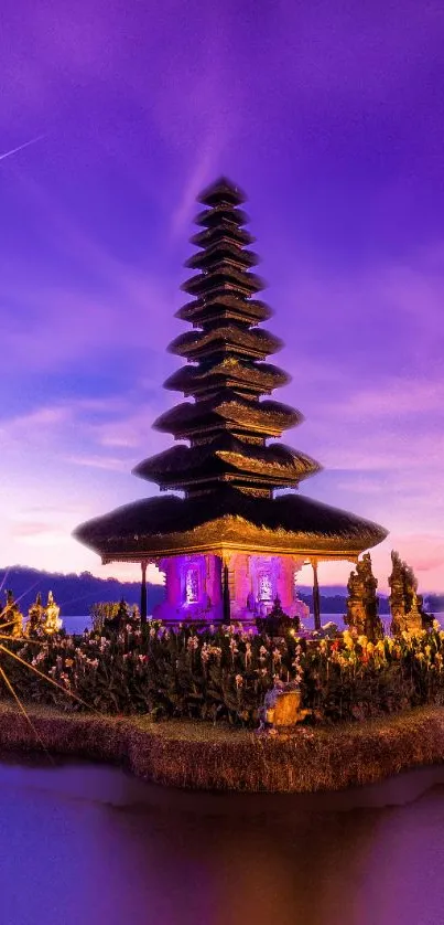 Balinese temple with a purple sky and tranquil waters at night.