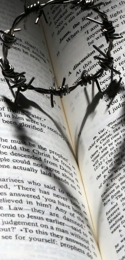 A heart-shaped barbed wire shadow cast on an open book's pages.