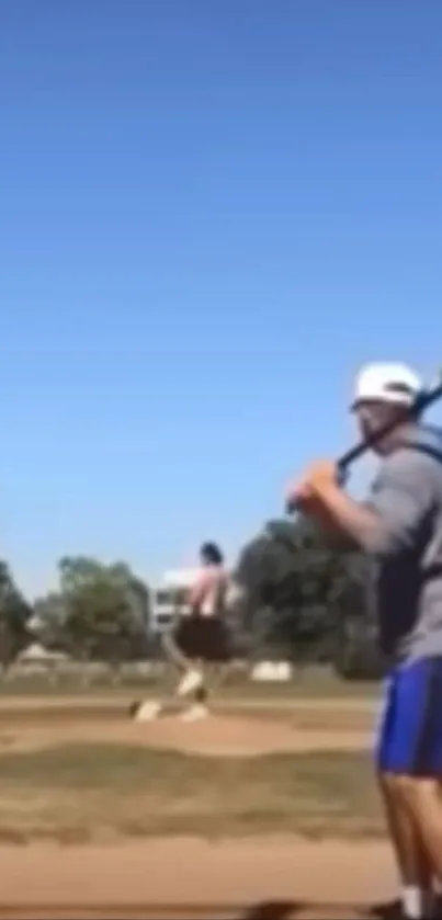 Baseball player about to swing under a clear blue sky.