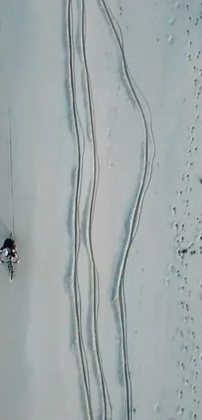 Aerial shot of a beach with a solo cyclist and ocean waves.