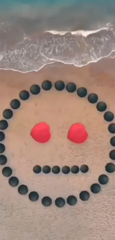 Creative beach art with stone smiley face and red heart eyes near ocean waves.