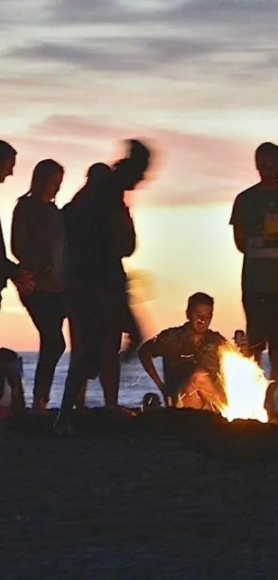 Beach bonfire with silhouettes at sunset.