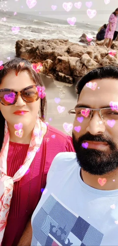 Couple at beach with pink heart overlays on a sunny day.