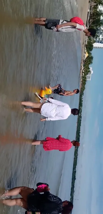 Family walking in shallow beach water under a clear sky.