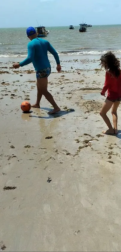 Man and child playing football on a sunny beach.