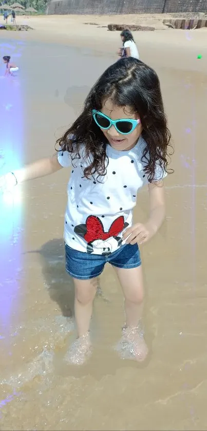 Child enjoying a playful day at the beach in sunglasses and casual wear.