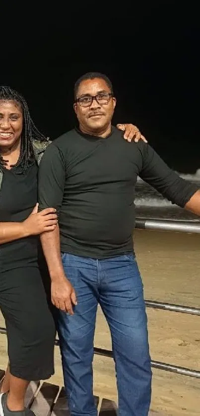 Couple enjoying a serene night at the beach with ocean waves in the background.