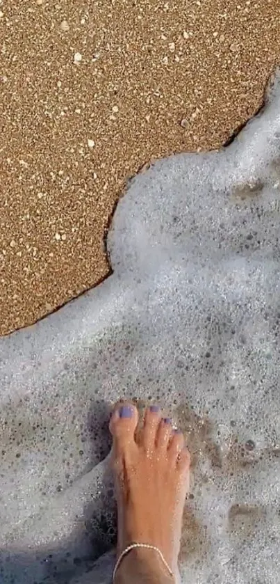 Foot on sandy beach with ocean waves approaching.