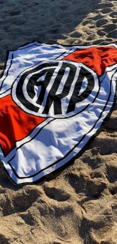 Beach sand with a logo towel spread under sunlight.