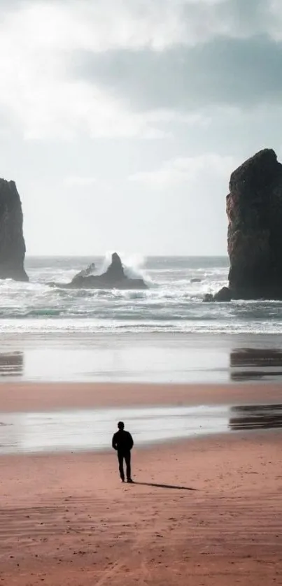 Solitary figure on a serene beach with towering rocks.