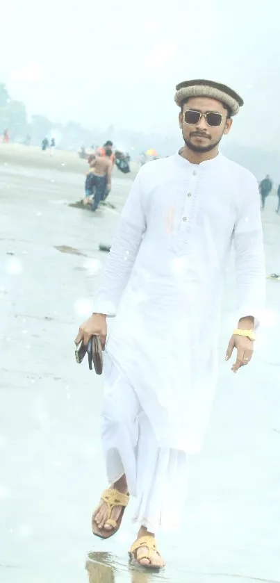 Man in white attire walking along a tranquil beach.