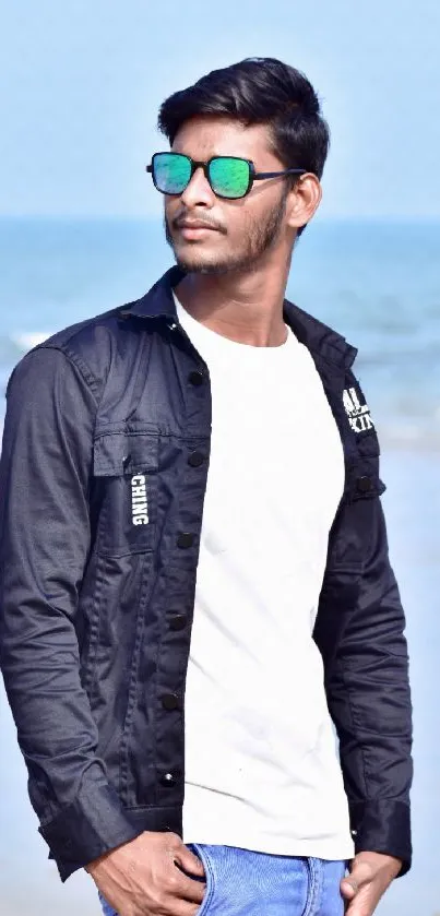 Stylish man in sunglasses with ocean backdrop.