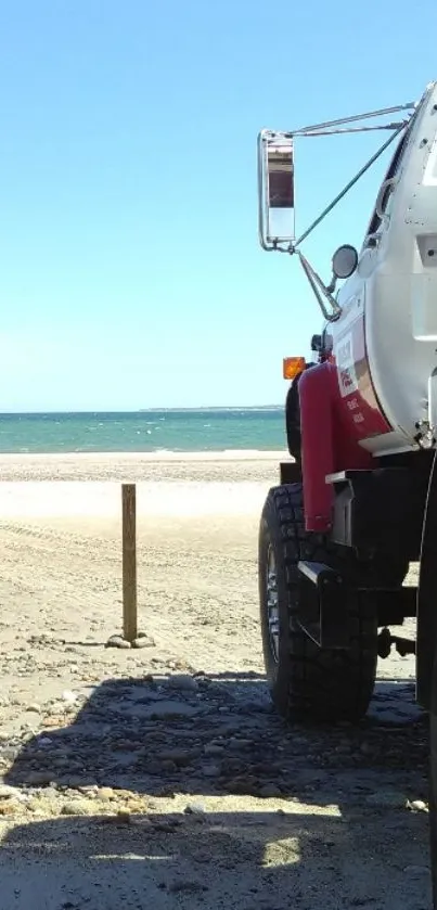 Truck parked on a sunny beach with ocean view.