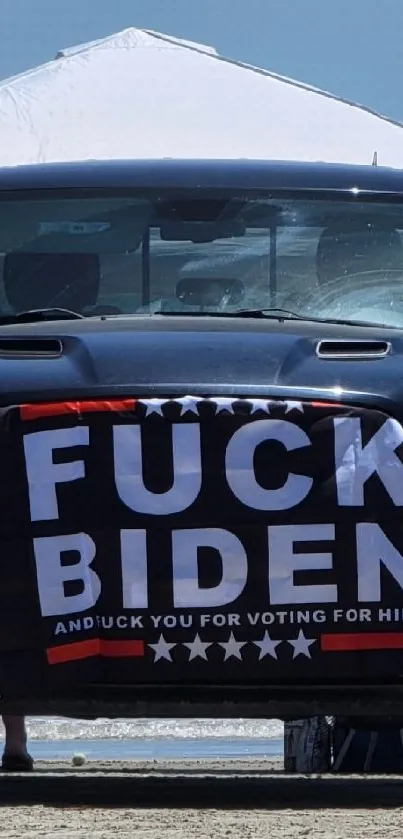 Truck with bold banner parked on a scenic beach.