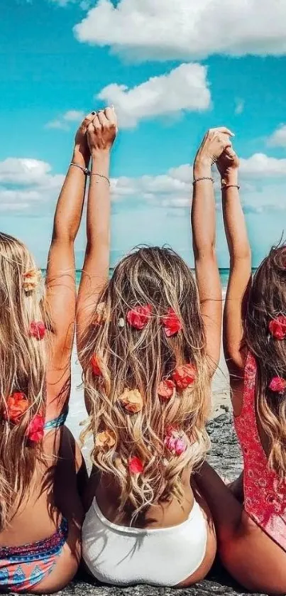 Three women with floral hair at beach, blue sky overhead.