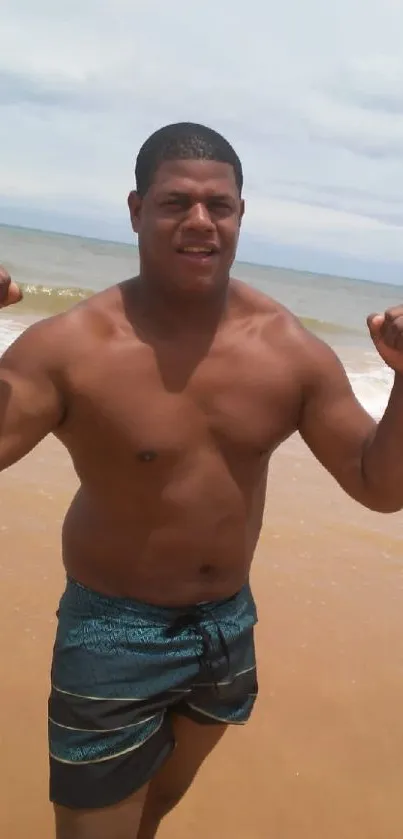 Person flexing at the beach with ocean backdrop.