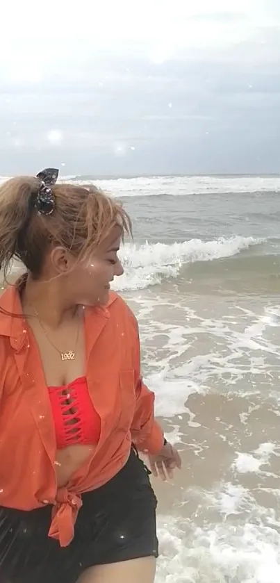 Woman enjoying waves on a beach under a cloudy sky.